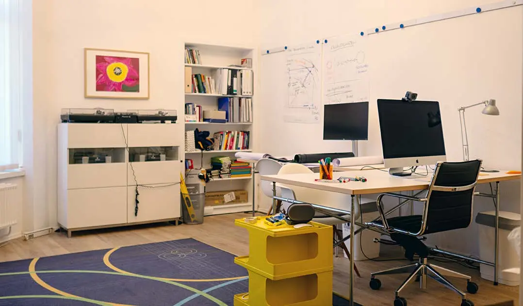Back Space mit großem Schreibtisch, Regalwand und blau gemustertem Teppich